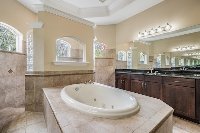 full bath with a tray ceiling, tile patterned floors, a jetted tub, vanity, and ornamental molding