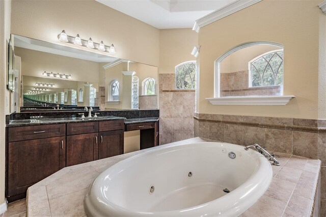 bathroom featuring ornamental molding, vanity, and a relaxing tiled tub