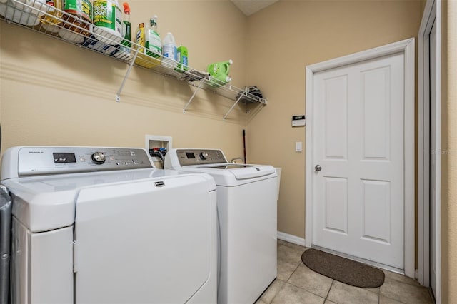 clothes washing area with baseboards, washer and dryer, laundry area, and light tile patterned floors