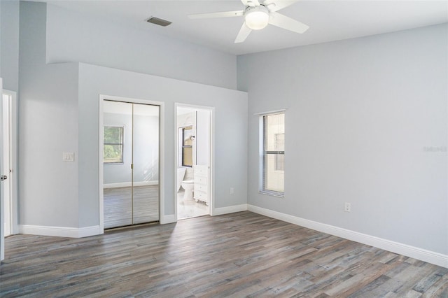 unfurnished bedroom featuring ceiling fan, dark hardwood / wood-style floors, connected bathroom, and a closet