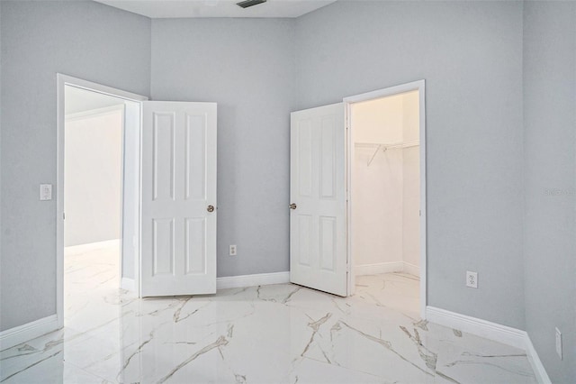 unfurnished bedroom with a high ceiling, a spacious closet, and a closet