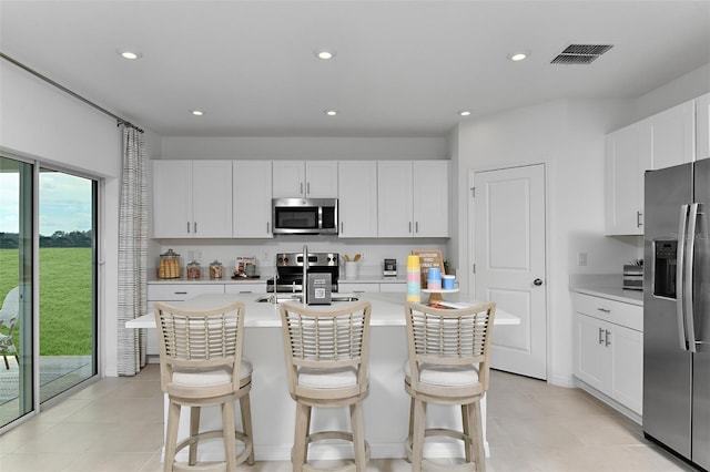 kitchen featuring an island with sink, a breakfast bar, stainless steel appliances, and white cabinets