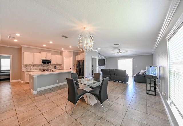 dining space featuring ceiling fan with notable chandelier, sink, light tile patterned floors, and crown molding