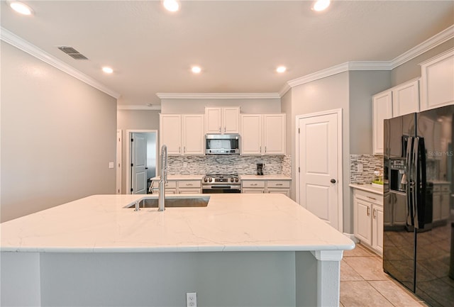 kitchen featuring white cabinetry, a center island with sink, appliances with stainless steel finishes, light tile patterned floors, and ornamental molding