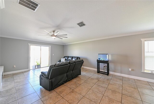 living room featuring a textured ceiling, ceiling fan, light tile patterned flooring, and crown molding