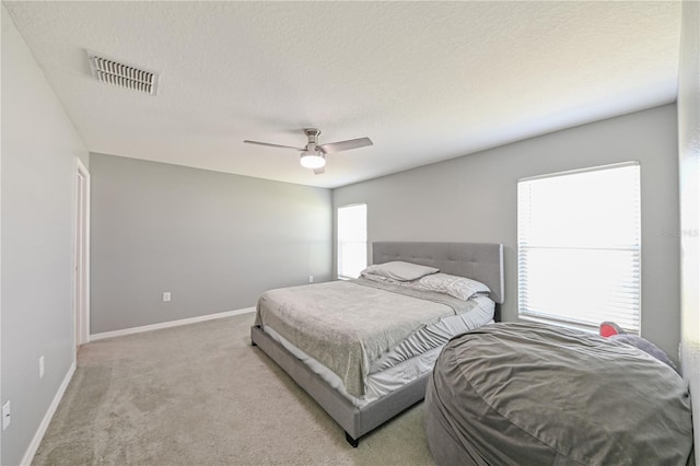 carpeted bedroom with multiple windows, a textured ceiling, and ceiling fan