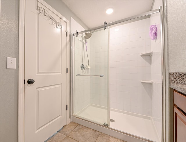 bathroom with a shower with door, vanity, and tile patterned floors