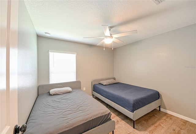 bedroom with light wood-type flooring, a textured ceiling, and ceiling fan