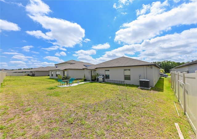 rear view of house with a lawn, a patio area, and central air condition unit