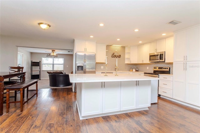 kitchen with a kitchen island with sink, stainless steel appliances, white cabinets, and dark wood-type flooring