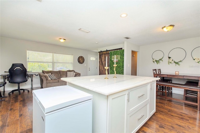 kitchen featuring a barn door, a kitchen island, dark hardwood / wood-style floors, and white cabinets