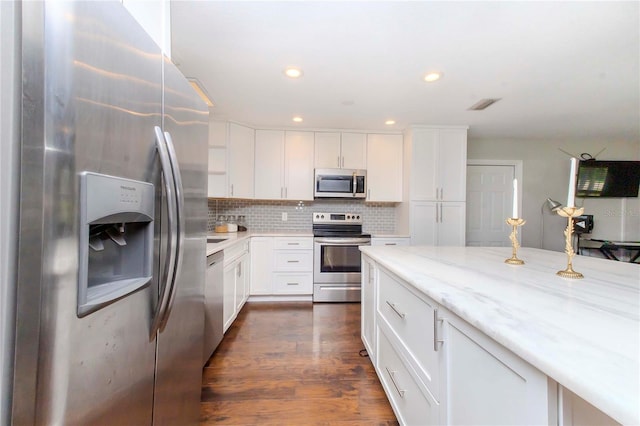 kitchen featuring white cabinetry, light stone counters, backsplash, stainless steel appliances, and dark hardwood / wood-style floors