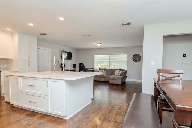 kitchen featuring a center island with sink, dark wood-type flooring, and white cabinets