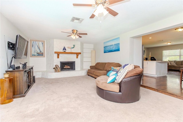 living room featuring ceiling fan, hardwood / wood-style flooring, and a fireplace