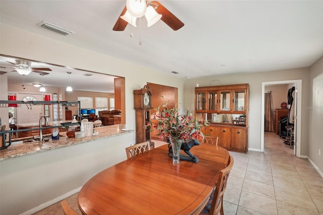 tiled dining area featuring ceiling fan and sink