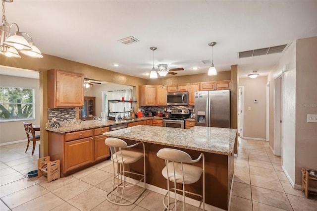 kitchen with a breakfast bar, kitchen peninsula, decorative backsplash, appliances with stainless steel finishes, and decorative light fixtures