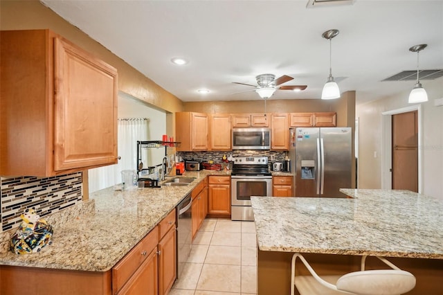 kitchen with light stone counters, pendant lighting, stainless steel appliances, and backsplash