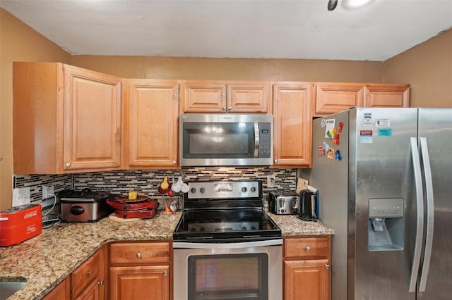 kitchen featuring appliances with stainless steel finishes, light brown cabinets, light stone counters, and tasteful backsplash