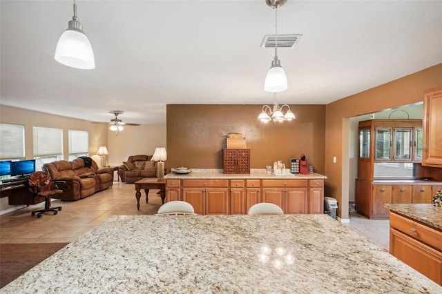 interior space featuring ceiling fan, light stone countertops, and decorative light fixtures