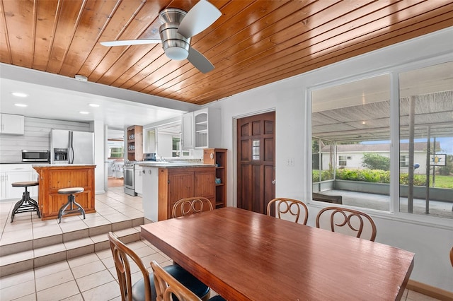 tiled dining room with ceiling fan and wooden ceiling