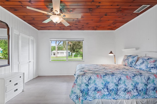 bedroom with wood ceiling, a closet, light wood-type flooring, crown molding, and ceiling fan