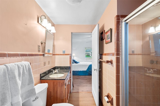 bathroom featuring vanity, wood-type flooring, walk in shower, tile walls, and toilet