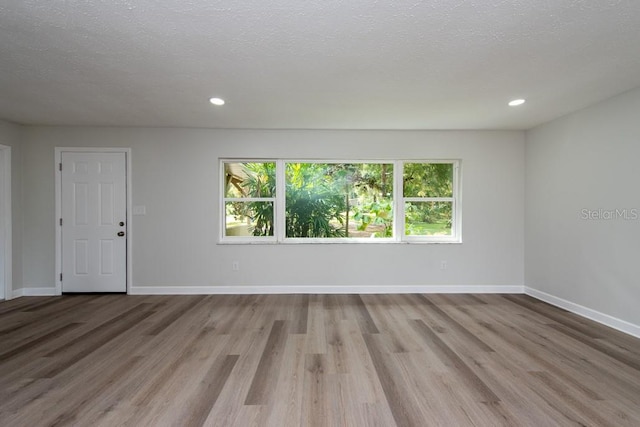 spare room with a textured ceiling and light hardwood / wood-style flooring