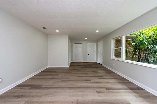 hall with light hardwood / wood-style flooring and a textured ceiling