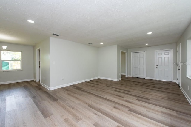 spare room with light wood-type flooring and a textured ceiling