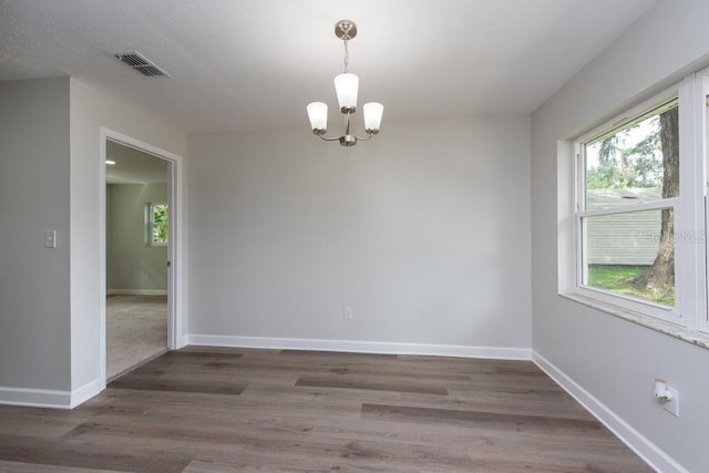 spare room featuring dark hardwood / wood-style flooring and an inviting chandelier