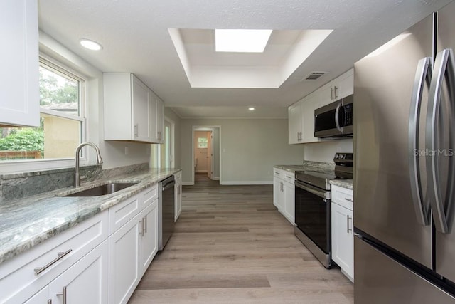 kitchen featuring sink, white cabinetry, stainless steel appliances, and a tray ceiling