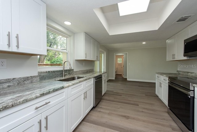 kitchen with a raised ceiling, sink, white cabinets, and stainless steel appliances