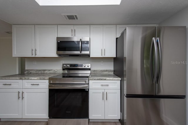 kitchen featuring white cabinetry, stainless steel appliances, and a textured ceiling