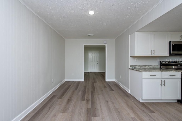 kitchen featuring white cabinets, range, and a textured ceiling