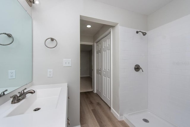 bathroom with tiled shower, vanity, and hardwood / wood-style flooring