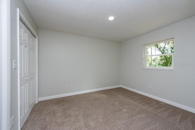 unfurnished bedroom with carpet floors, a textured ceiling, and a closet