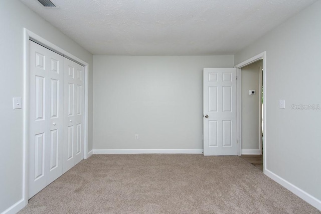 unfurnished bedroom with light colored carpet, a textured ceiling, and a closet