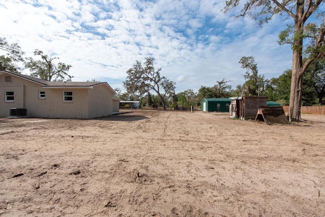 view of yard featuring central AC unit and a storage shed