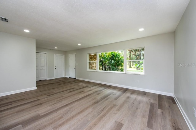 spare room with a textured ceiling and light wood-type flooring