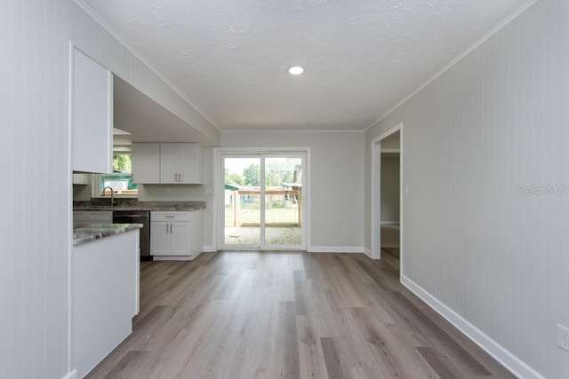 kitchen with white cabinetry, sink, light hardwood / wood-style flooring, stainless steel dishwasher, and ornamental molding