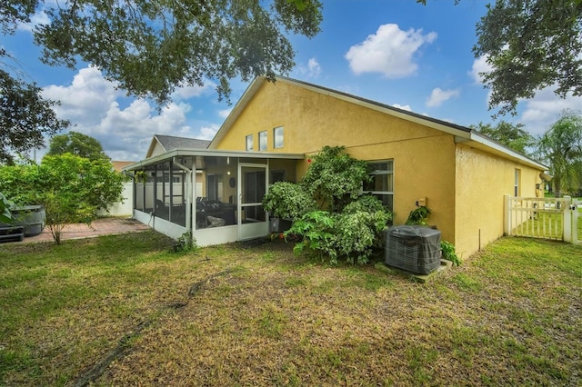 back of property featuring a lawn, a sunroom, and central AC