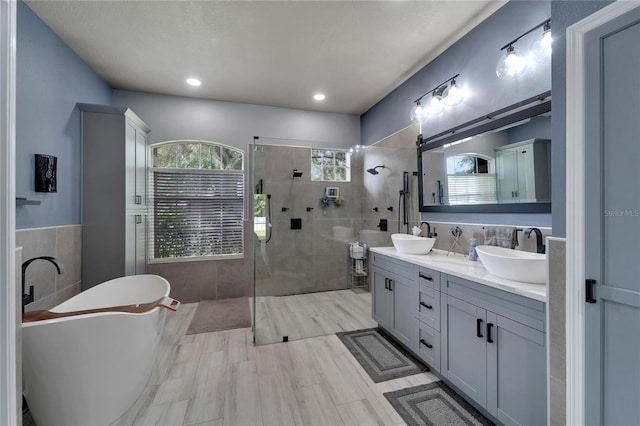 bathroom featuring independent shower and bath, vanity, tile walls, and wood-type flooring