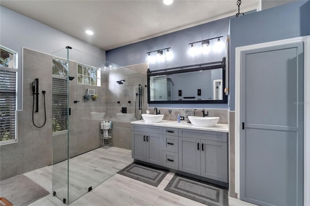 bathroom with a tile shower, vanity, and tile walls