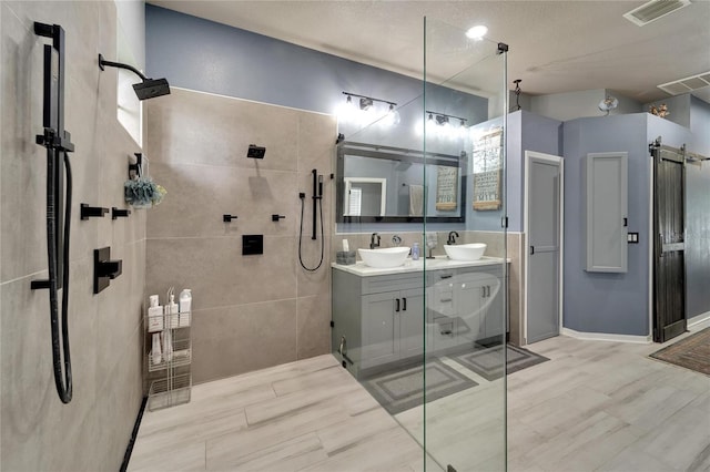 bathroom featuring hardwood / wood-style flooring, a shower with door, vanity, and a textured ceiling