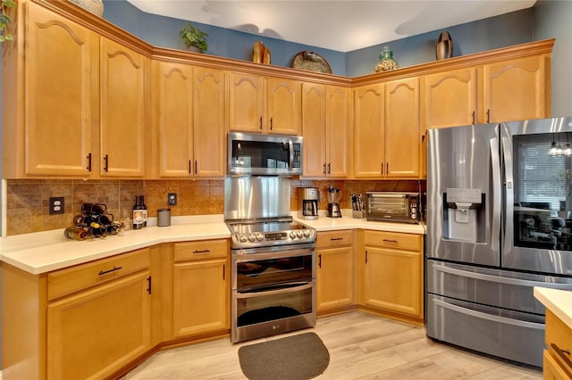 kitchen with stainless steel appliances, light wood-type flooring, and tasteful backsplash