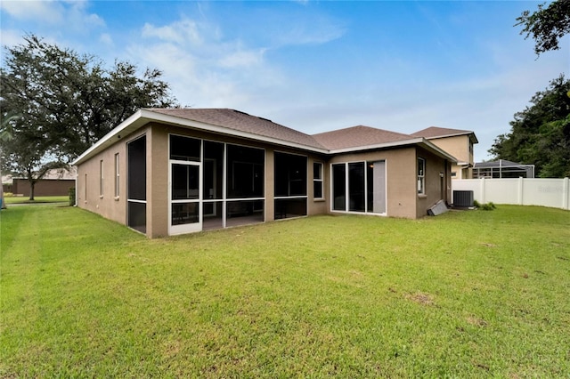 rear view of property featuring a lawn, a sunroom, and central AC