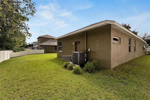 exterior space featuring central air condition unit and a yard