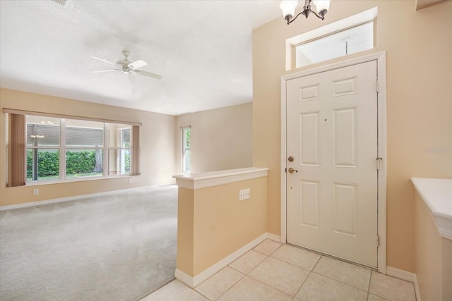 carpeted foyer with ceiling fan with notable chandelier