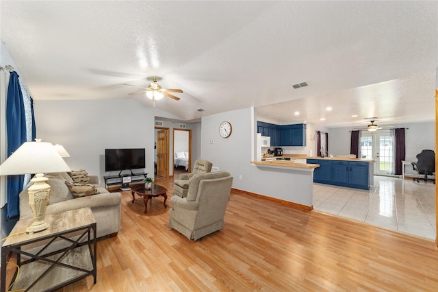 living room featuring ceiling fan, a textured ceiling, light hardwood / wood-style flooring, and lofted ceiling