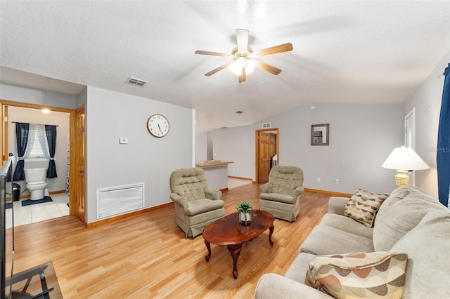 living room with vaulted ceiling, light hardwood / wood-style floors, ceiling fan, and a textured ceiling